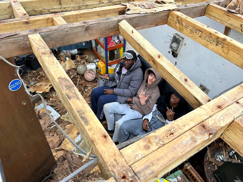 Three of the crew taking a break under the roof frame of a garden building
