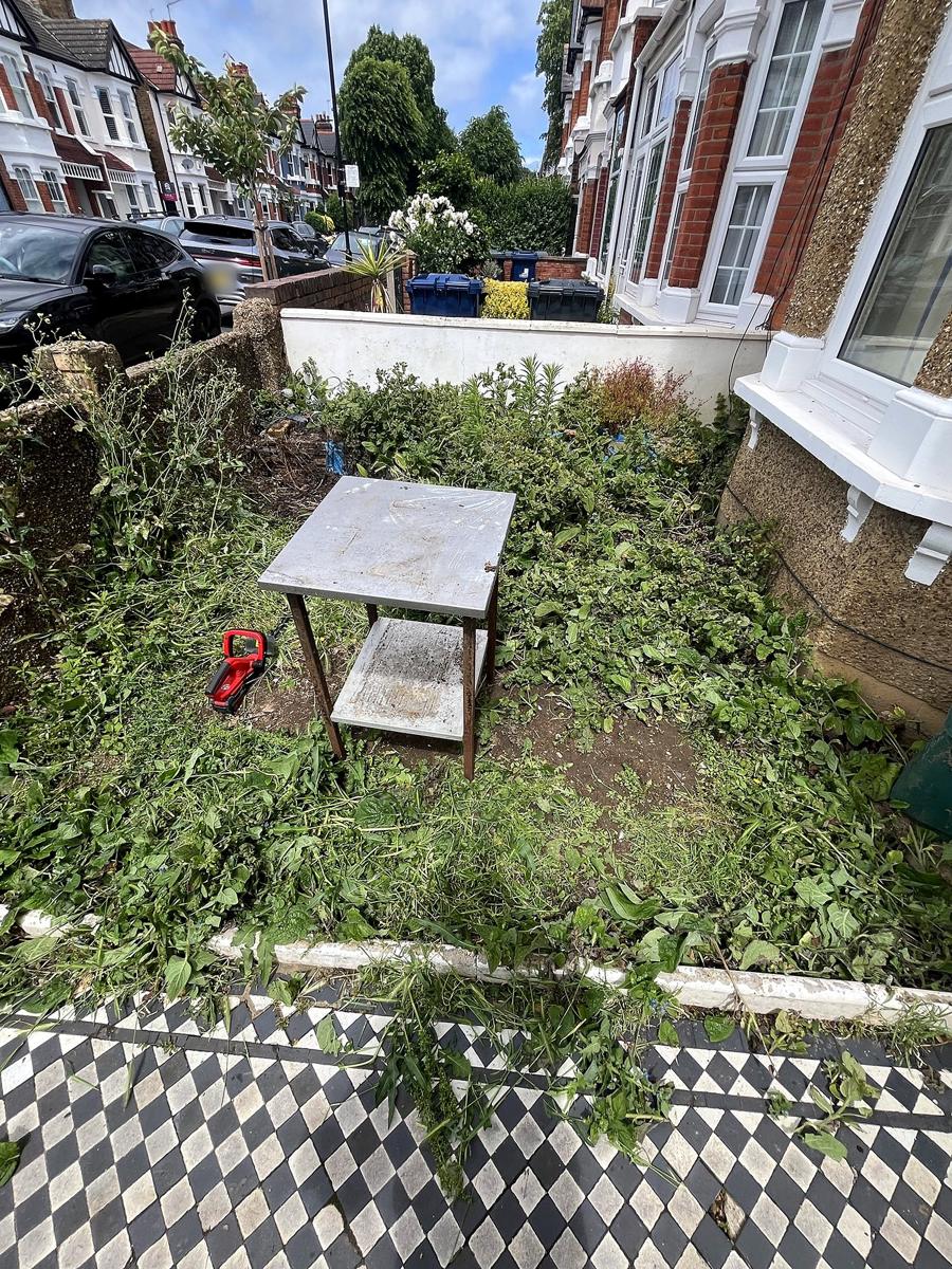 Front garden full of weeds with a steel table